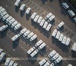 Aerial drone shot of neatly organized vans in a large parking lot.